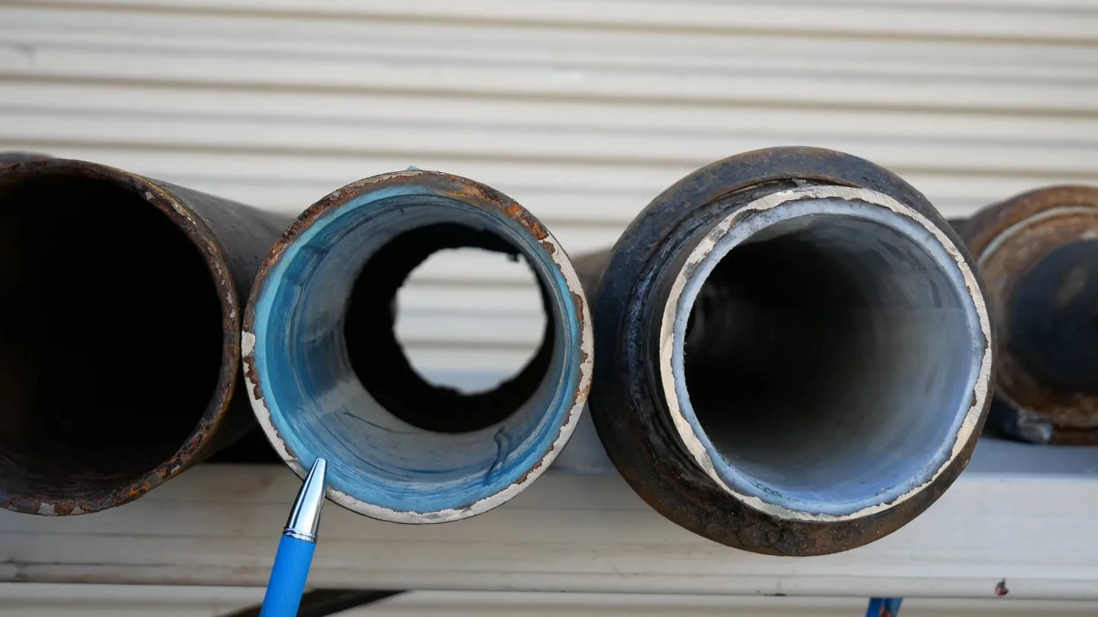 Cut sections of pipe showing blue and white liners cured inside them.