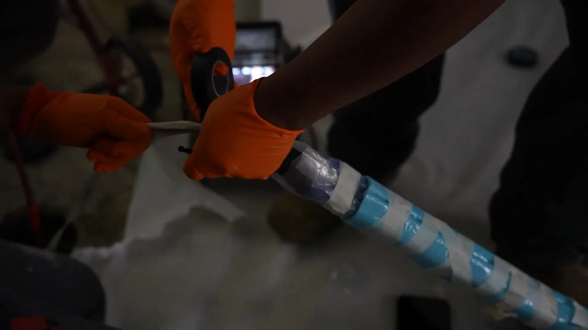 Gloved hands feeding a blue and white wrapped lining tube.